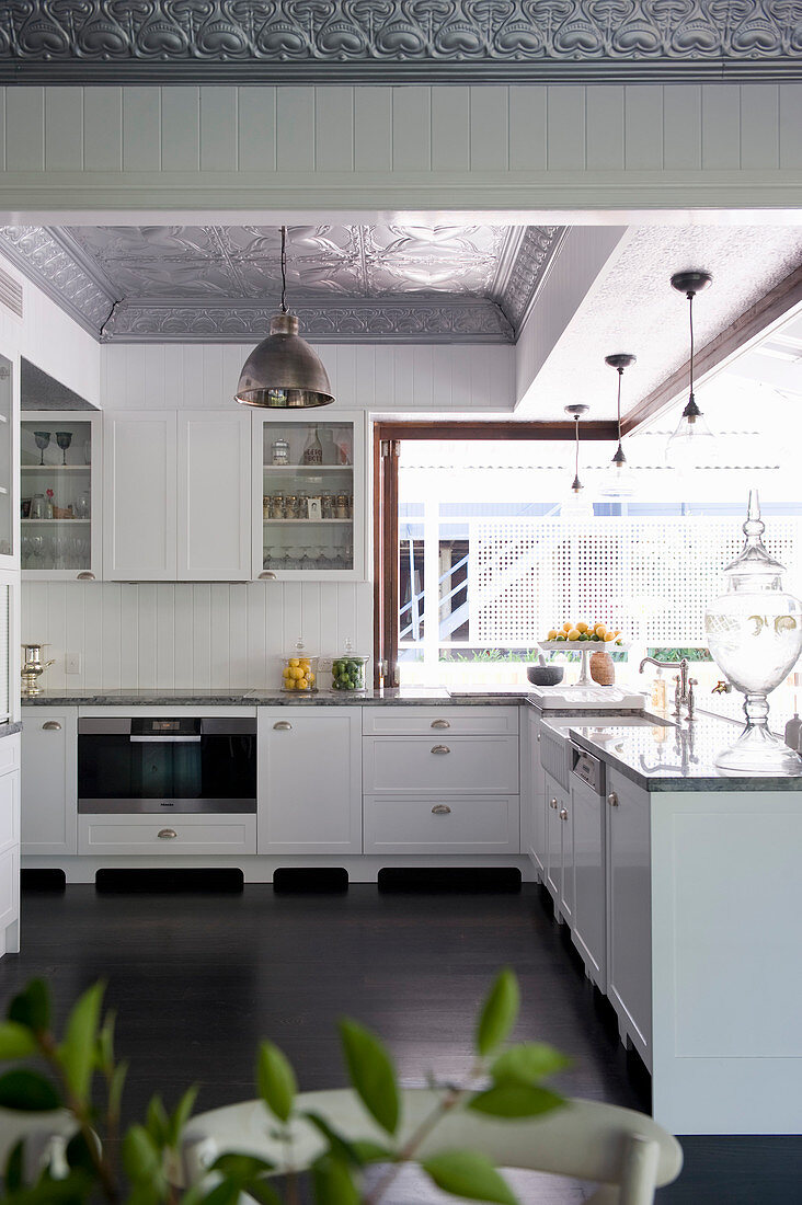 Offene Küche mit weißen Unterschränken übereck und dunklem Holzboden