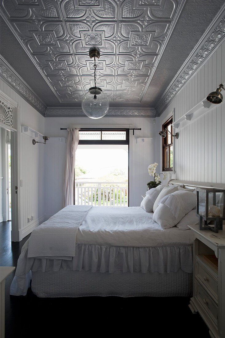 Doppelbett im Schlafzimmer mit silberfarbener Stuckdecke