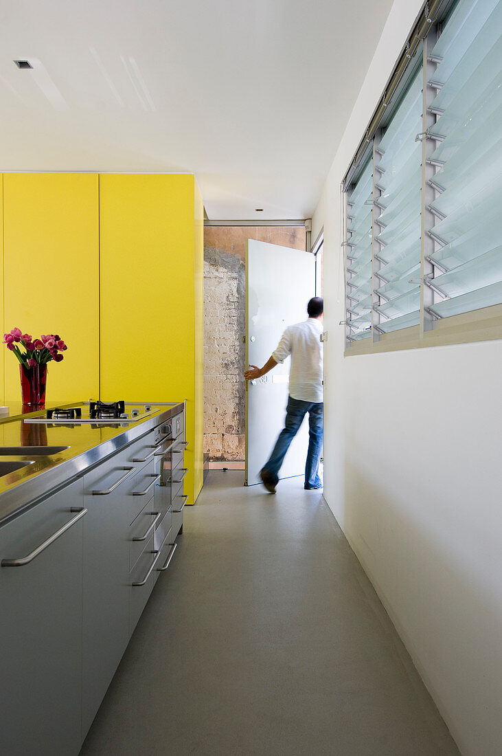 Moderne Küchenzeile und deckenhohe gelbe Schrankwand in Architektenhaus