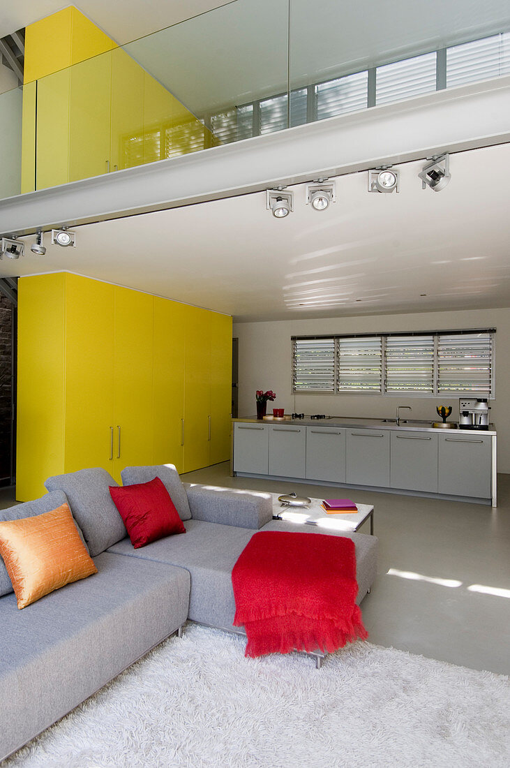 Offener Wohnraum in Architektenhaus mit Galerie und etagenübergreifender gelber Schrankwand