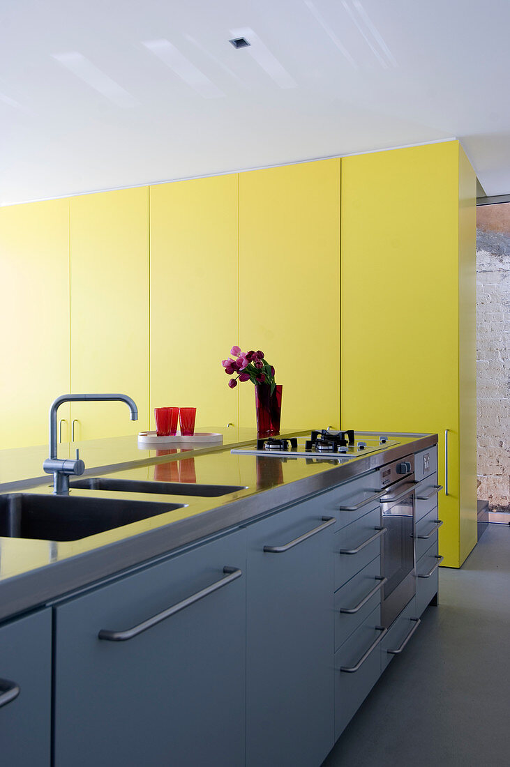 Moderne Küchenzeile und deckenhohe gelbe Schrankwand in Architektenhaus