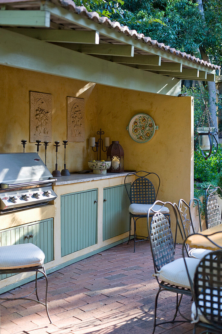 Terrassenbereich im nostalgischen Landhausstil mit überdachter Outdoor-Küchenzeile und Grill