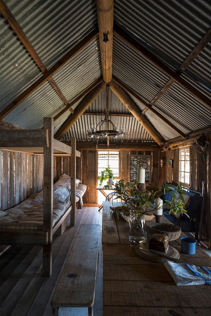 Schlafplätze und Esstisch mit Holzbank in einfacher Holzhütte
