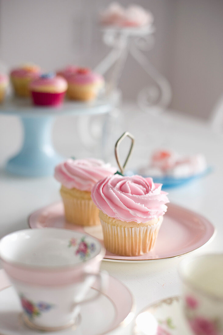 Cupcakes with pink frosting on table set in romantic style