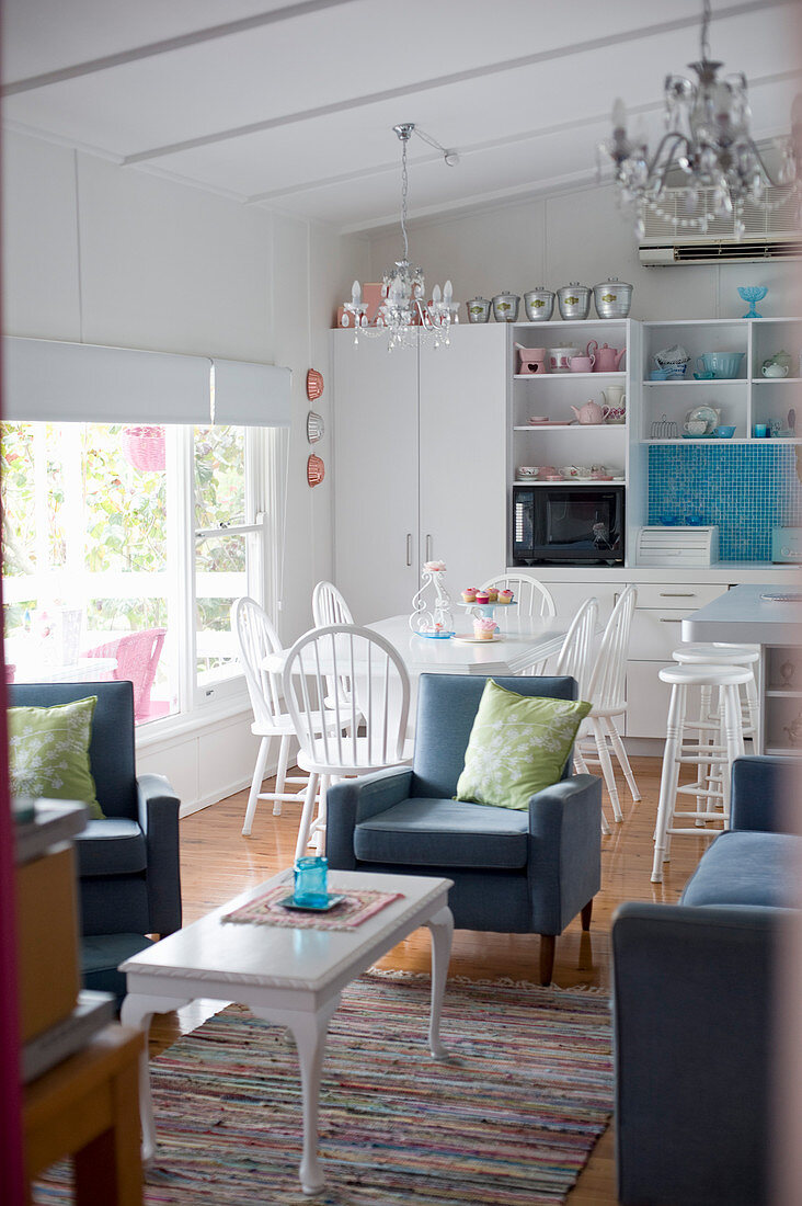 Bright open-plan interior in white and blue with kitchen, dining table and seating area