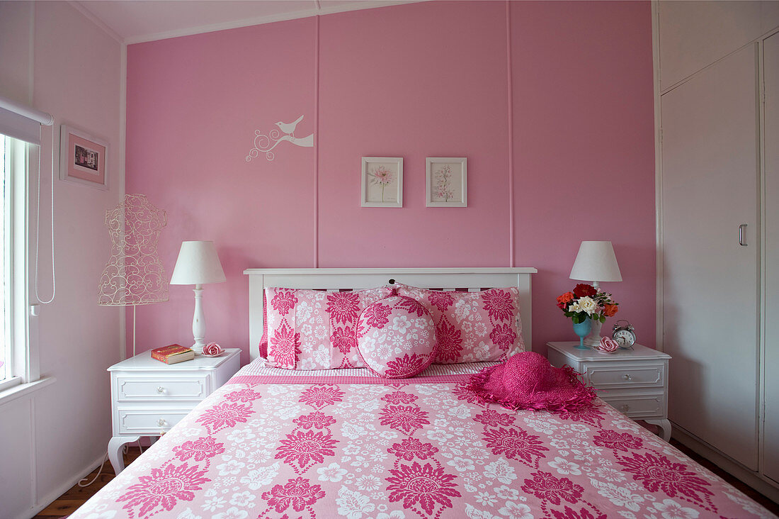 Feminines Schlafzimmer in Rosa mit weißem Holzbett und weißen Nachtschränkchen