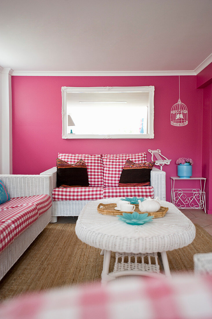White rattan furniture and pink walls in living room of beach house
