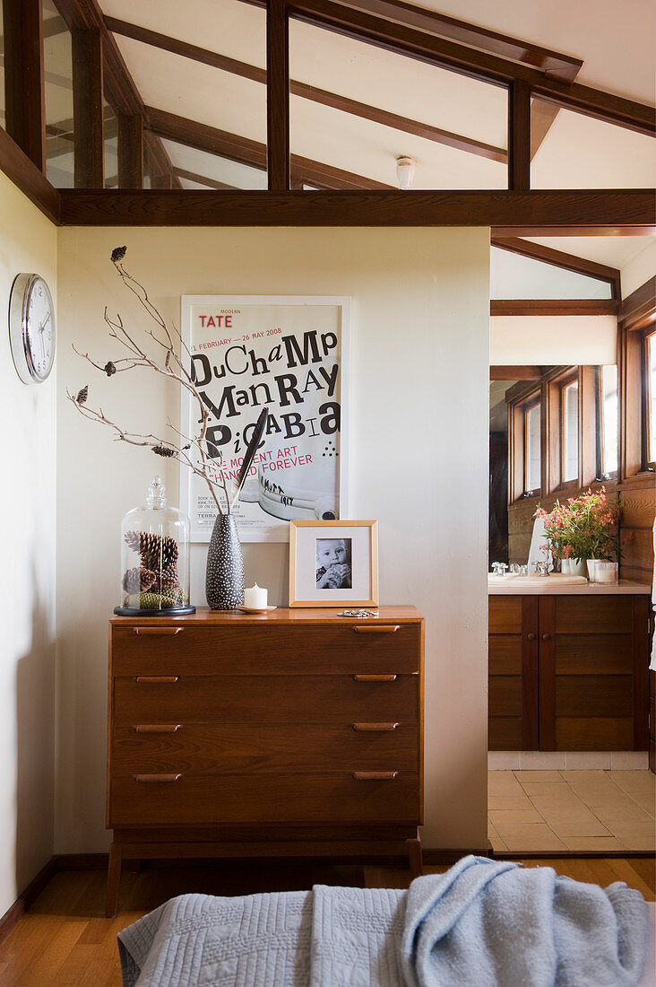 Chest of drawers in bedroom below sloping ceiling and exposed wooden ceiling beams