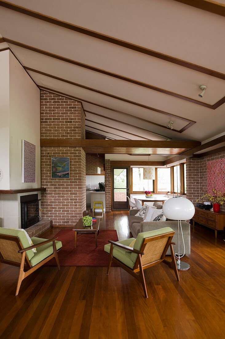 Fifties-style interior with seating area around fireplace, wooden floor and brick walls