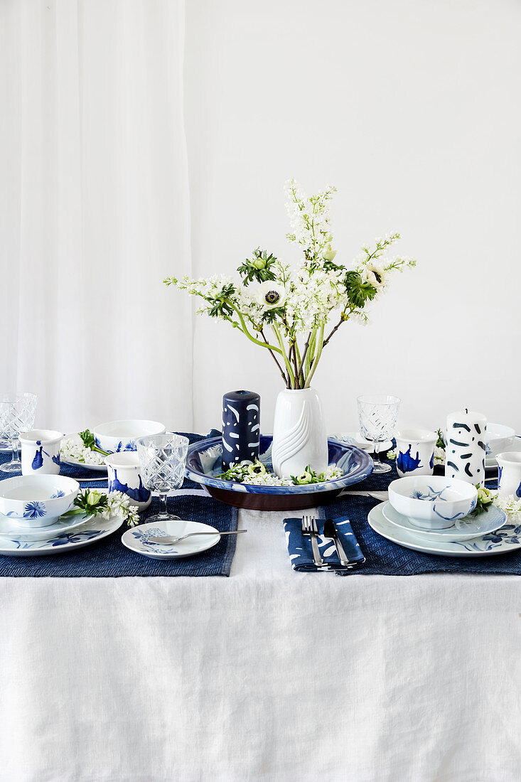 Blau-weiß gedeckter Tisch mit Frühlingsblumen