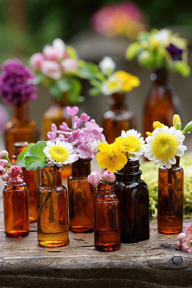 Buttercup, wildflower, lilac, and hawthorn flowers in brown bottles