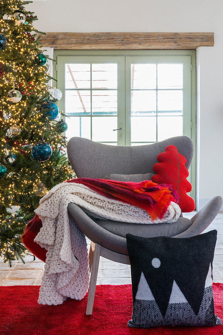 Kissen und Plaids auf modernem grauen Sessel am Weihnachtsbaum