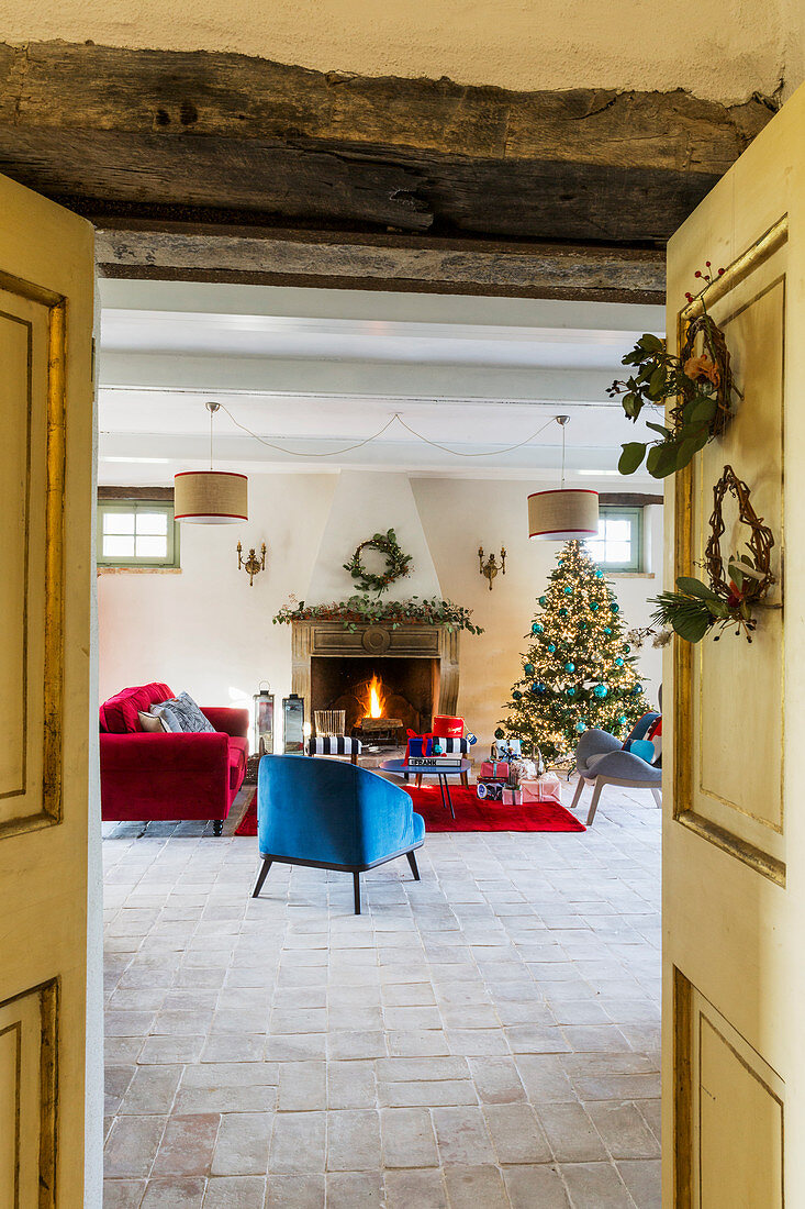Weihnachtsbaum und Möbel in Blau und Rot vorm offenen Kamin
