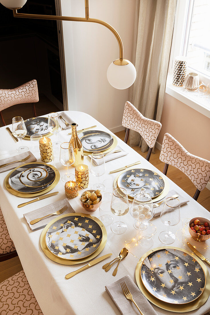 Teller mit Portraits auf weihnachtlich gedecktem Tisch in Gold und Weiß