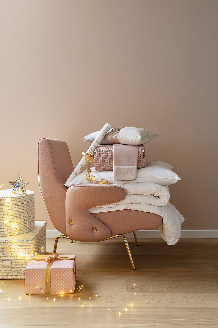 Gifts, blankets and cushions on pink armchair