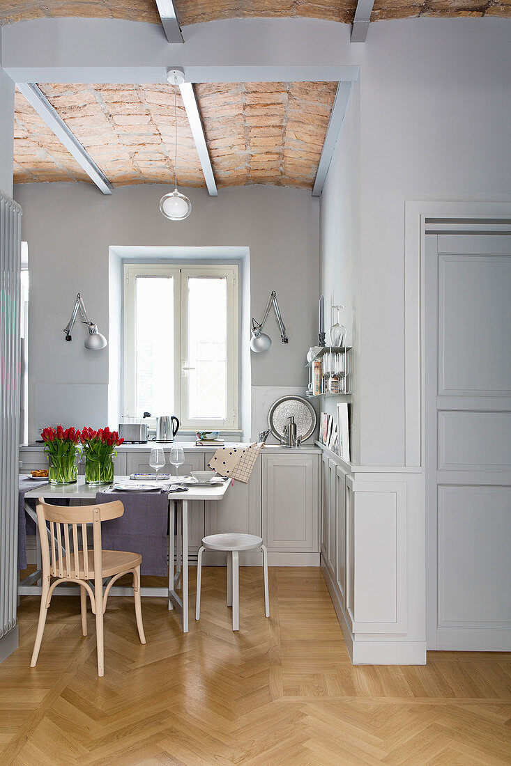 Esstisch in der offenen Küche mit grauen Wänden und Parkettboden