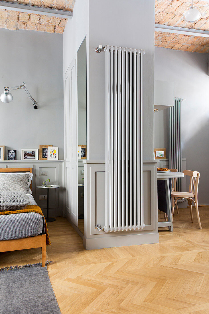 Radiator mounted on wall in studio apartment decorated in shades of grey