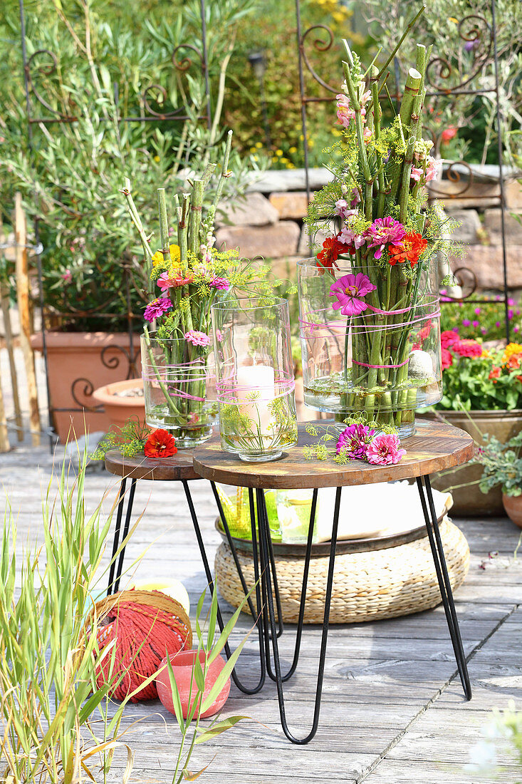 Vasen mit Gestecken aus Knöterich und Blumen auf dem Tisch auf der Terrasse