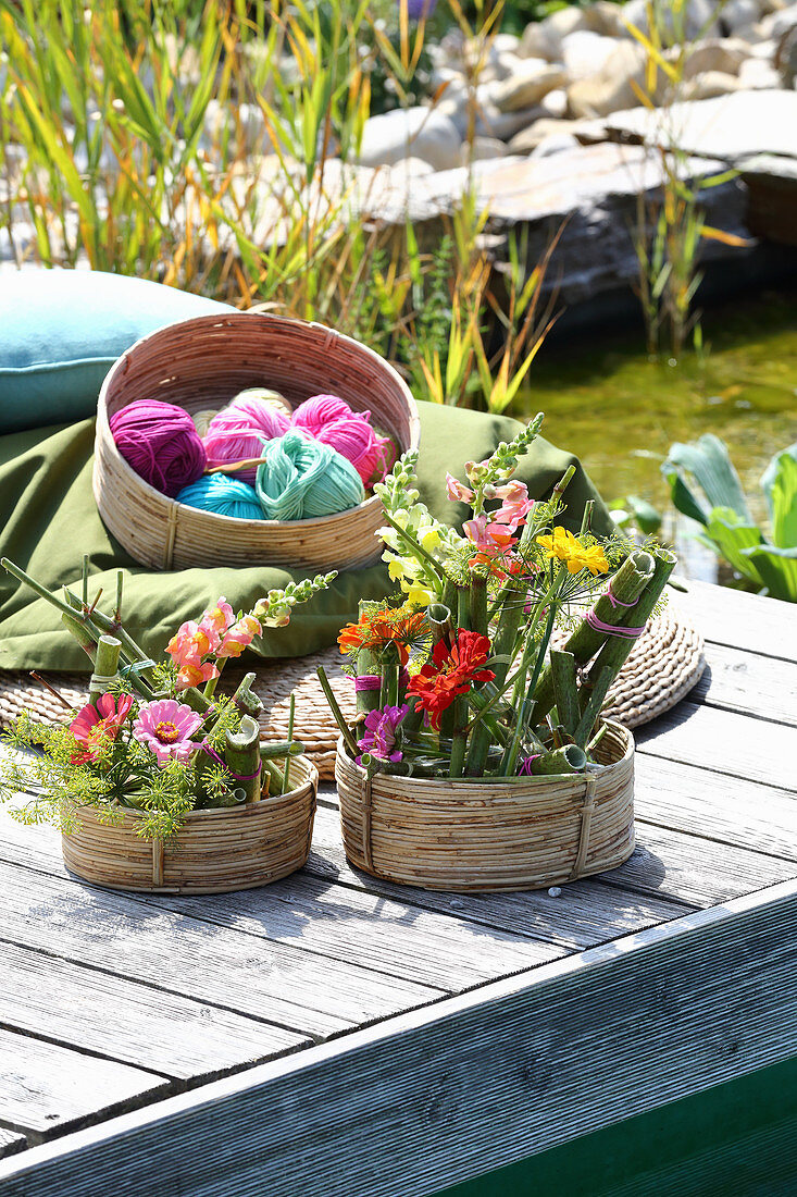 Arrangements of knotweed, snapdragons and zinnias in baskets on jetty