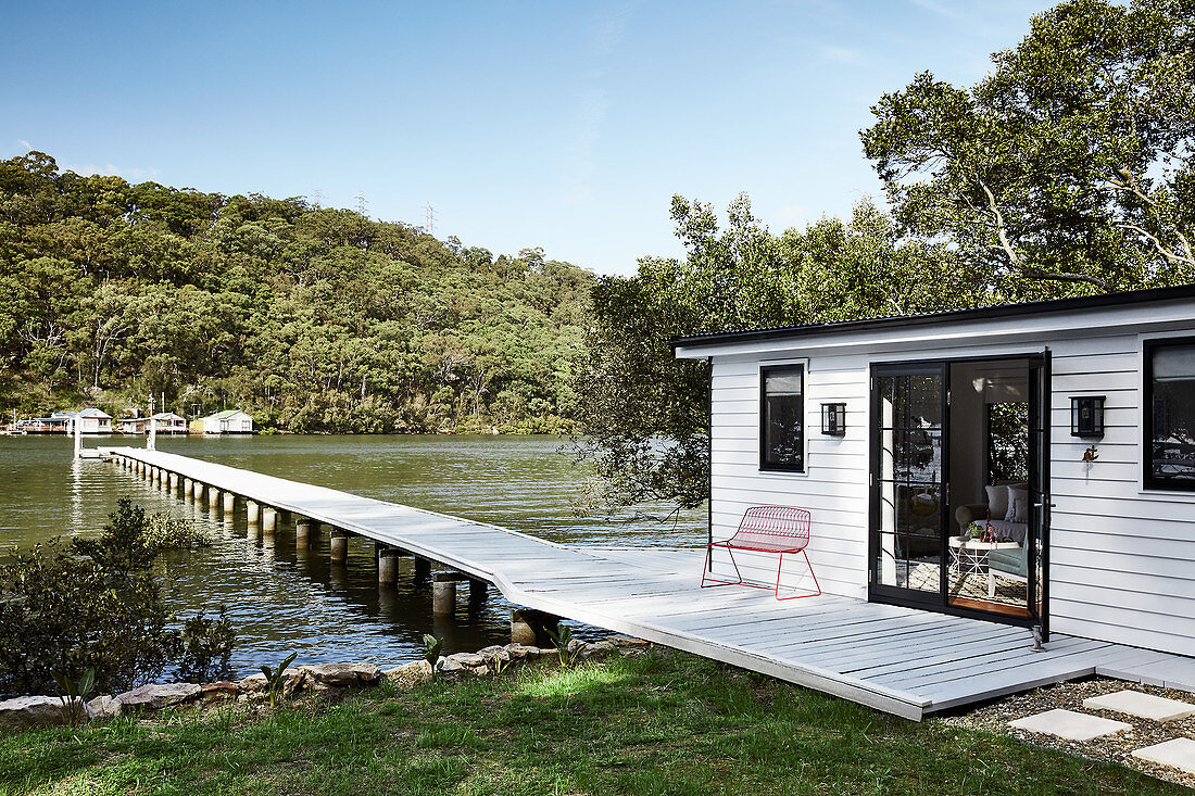Small house with white clapboard façade next to lake jetty