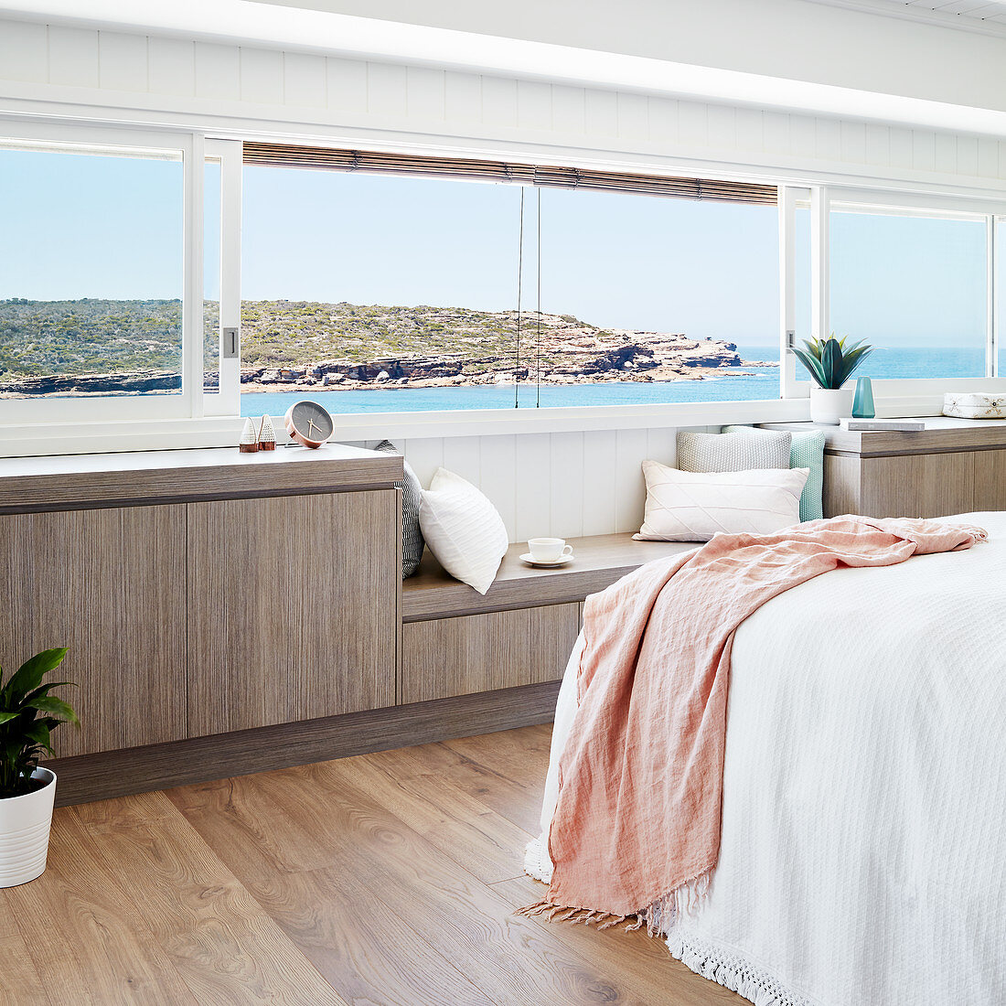 Sideboard with integrated window seat below horizontal panoramic window in bedroom