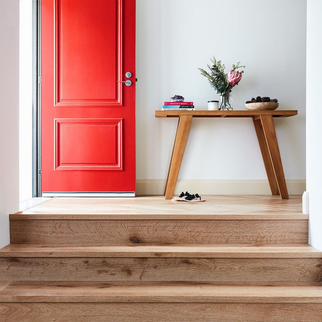 Stufen zum Flur mit Konsolentisch und offener roter Haustür