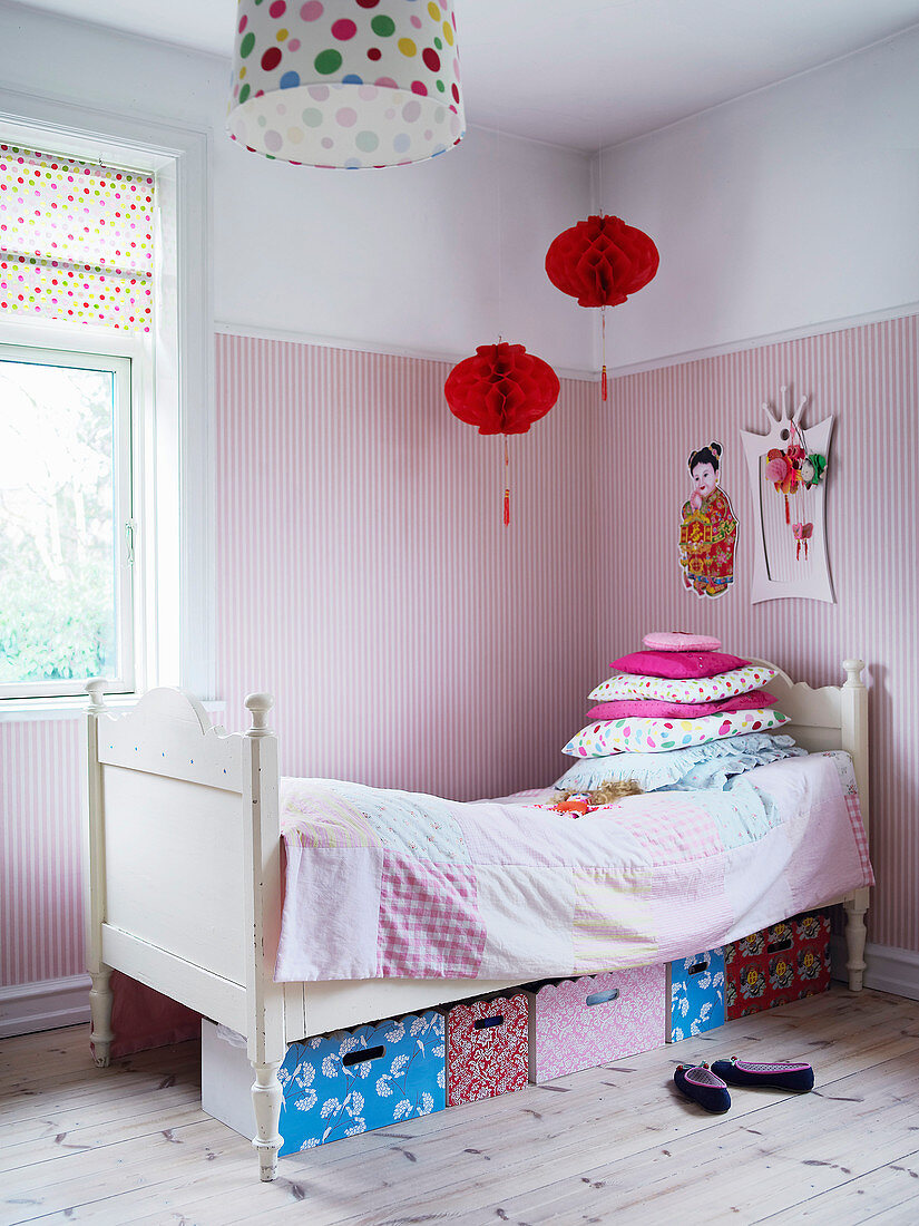 Boxes below bed in child's bedroom decorated in pink