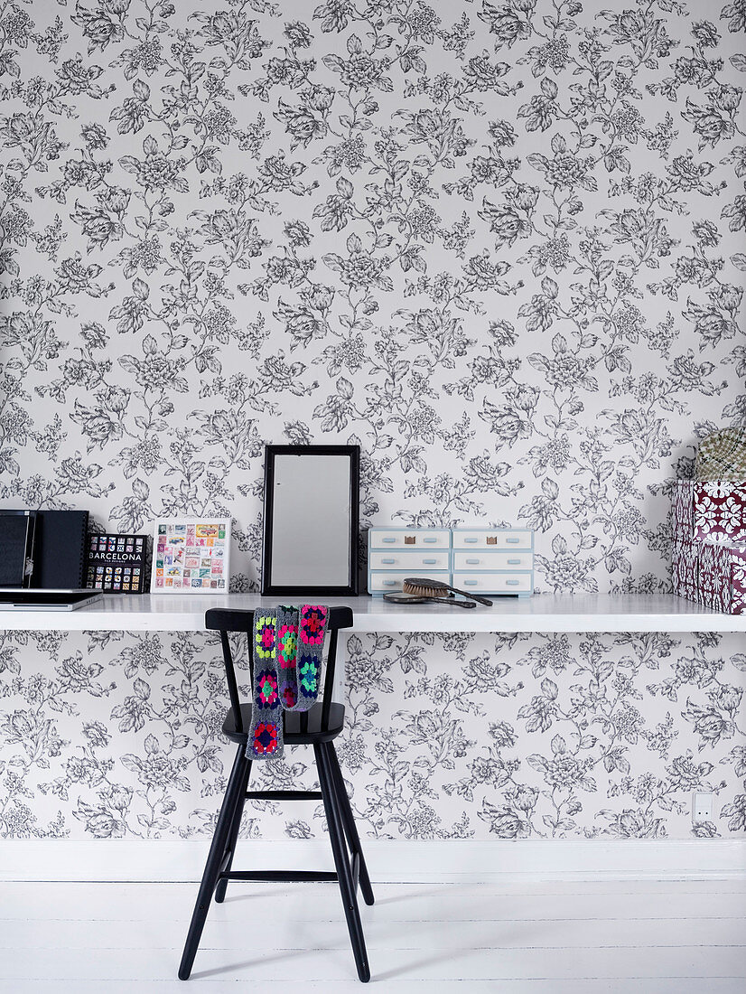 High chair at floating desk against floral wallpaper