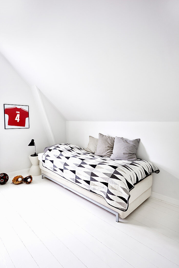 Bett mit grafisch gemustertem Plaid im minimalistischen Kinderzimmer