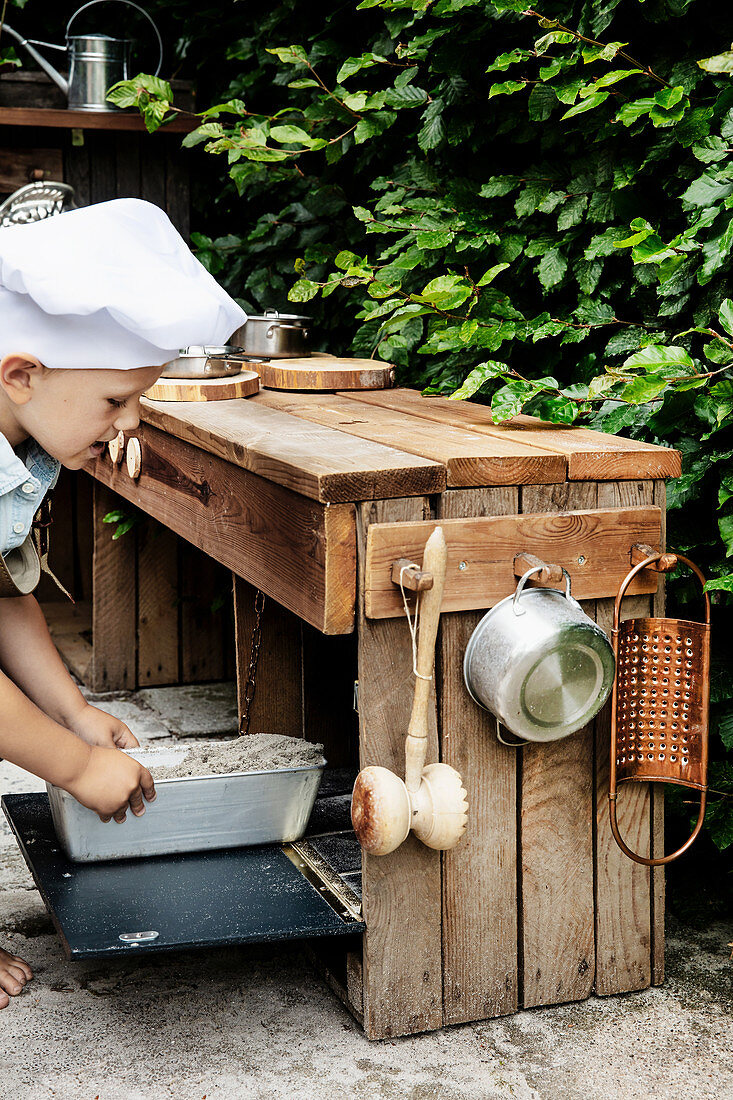 Little boy playing in DIY outdoor play kitchen