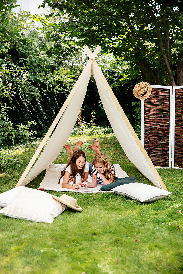 Zwei Mädchen spielen in einem Zelt im Garten mit Sitzplatz