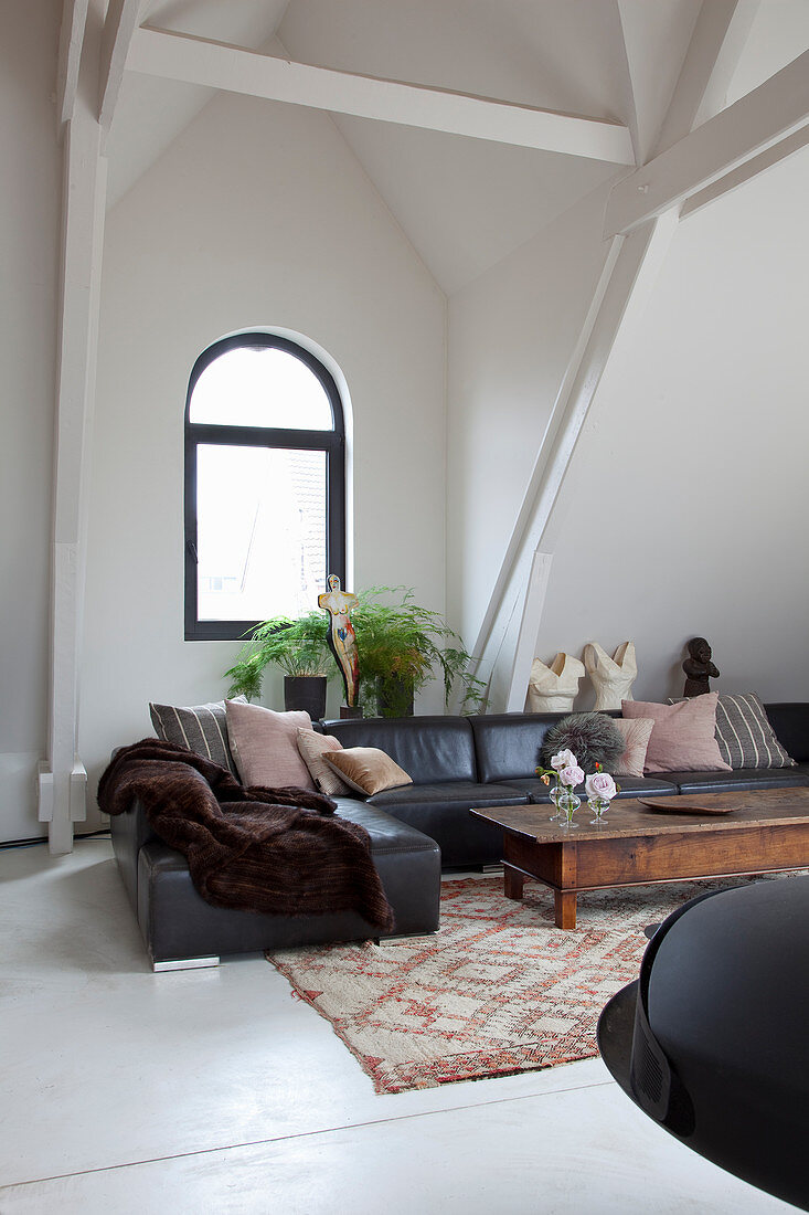 Black leather sofa and arched window in living room