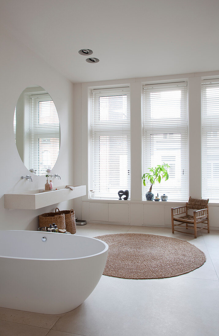 Free-standing bathtub in large bathroom decorated entirely in white