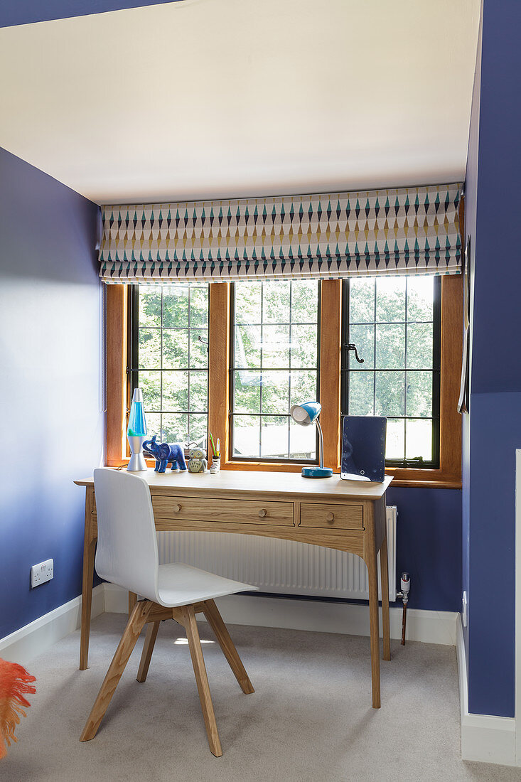 Schreibtisch vor Sprossenfenster im Zimmer mit blauen Wänden