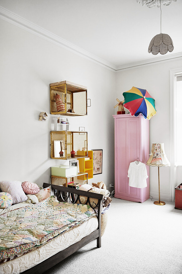 Bett, Wandregale aus alten Kisten und rosa Kleiderschrank im Mädchenzimmer