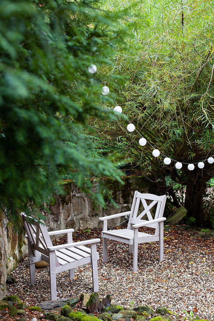 Zwei Holzstühle und Lichterkette im Garten