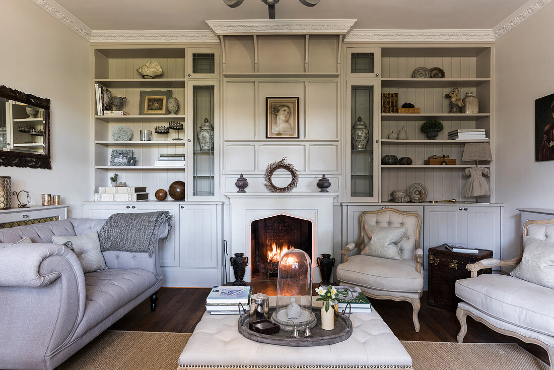 Lit fire with buttoned sofas and recessed shelving