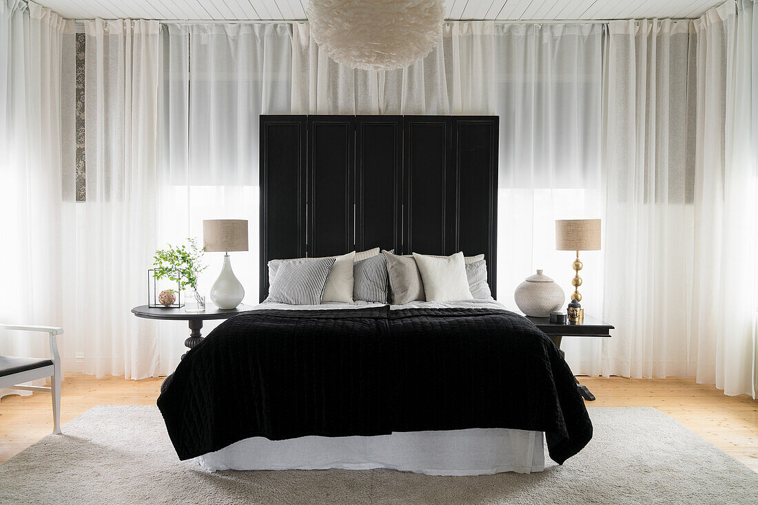 Doppelbett mit Paravent als Bettkopfteil im Schlafzimmer mit rundum Vorhang