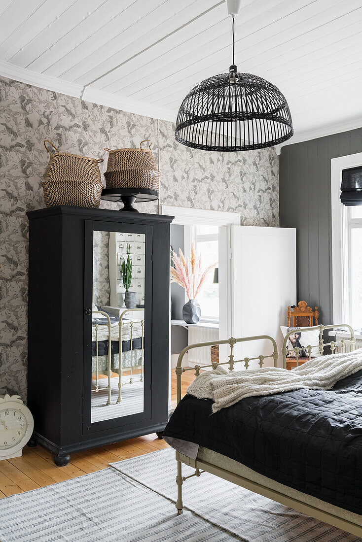 Black wardrobe with mirrored door and old metal twin beds in the guest room