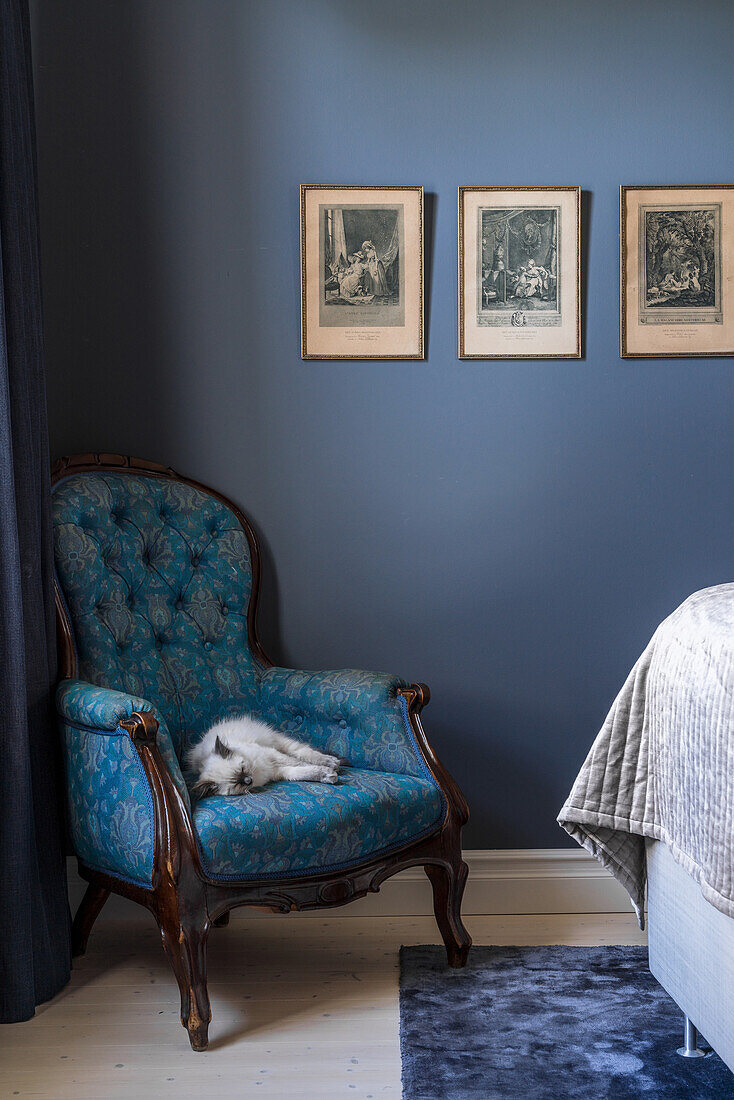 Blau gemusterter Sessel vor blauer Wand im Schlafzimmer