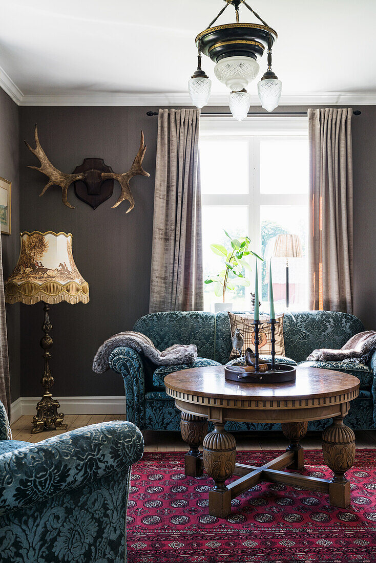 Sofa set, antique coffee table, floor lamp and antlers in the living room