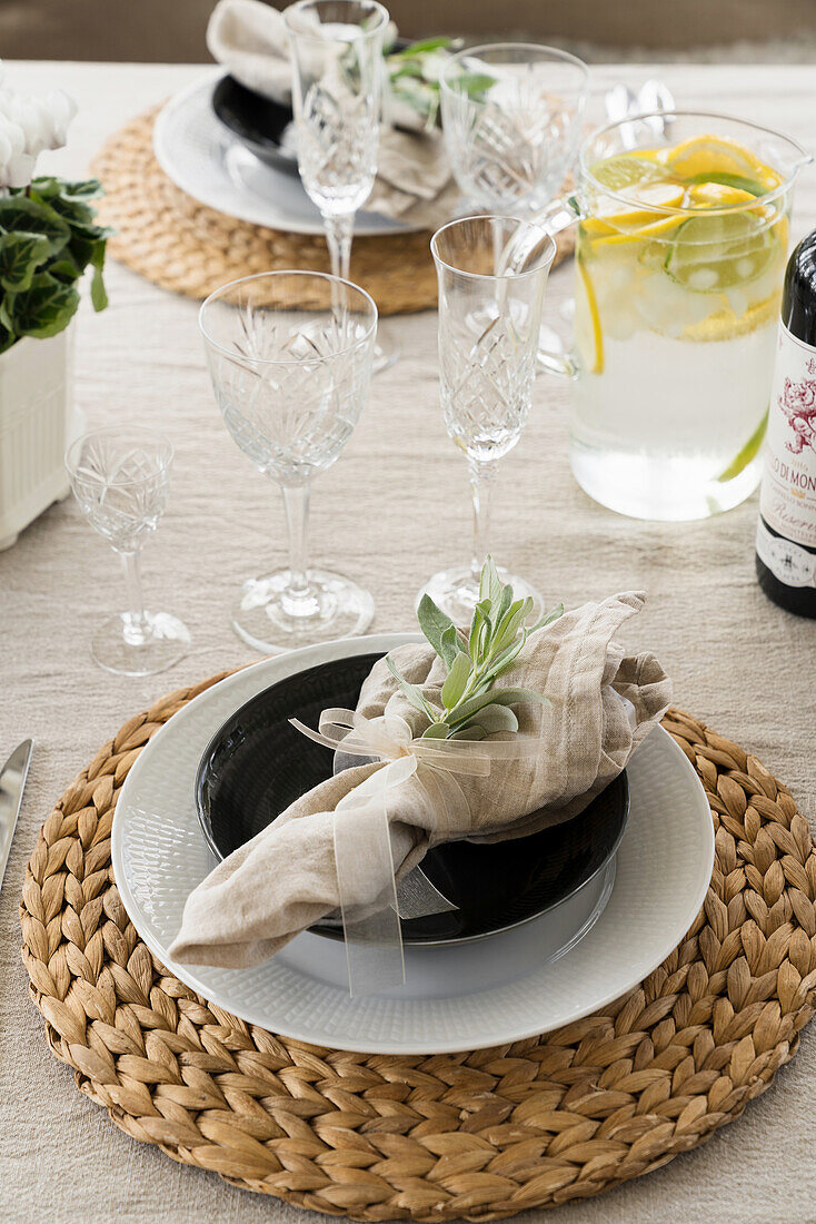 Festive place setting on round jute placemat, crystal glasses and pitcher of lemonade