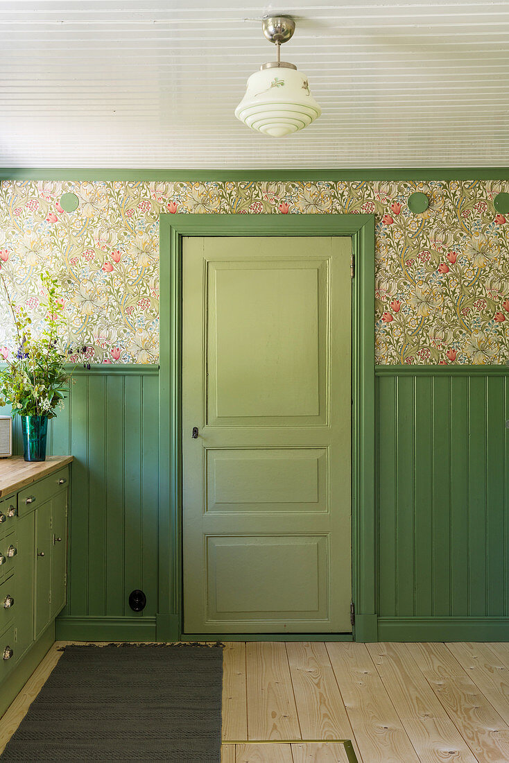 Grüne Tür, farblich passende Holzverkleidung und Tapete in der Küche