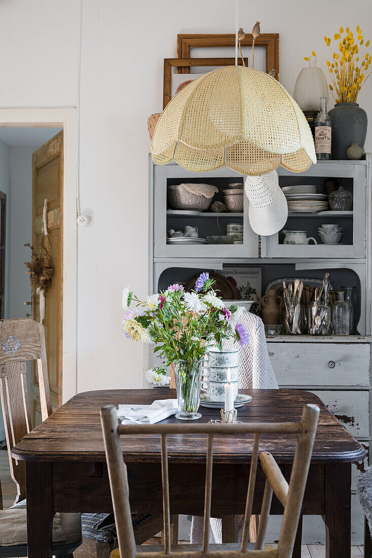 Holztisch, darüber Lampe in ländlicher Küche