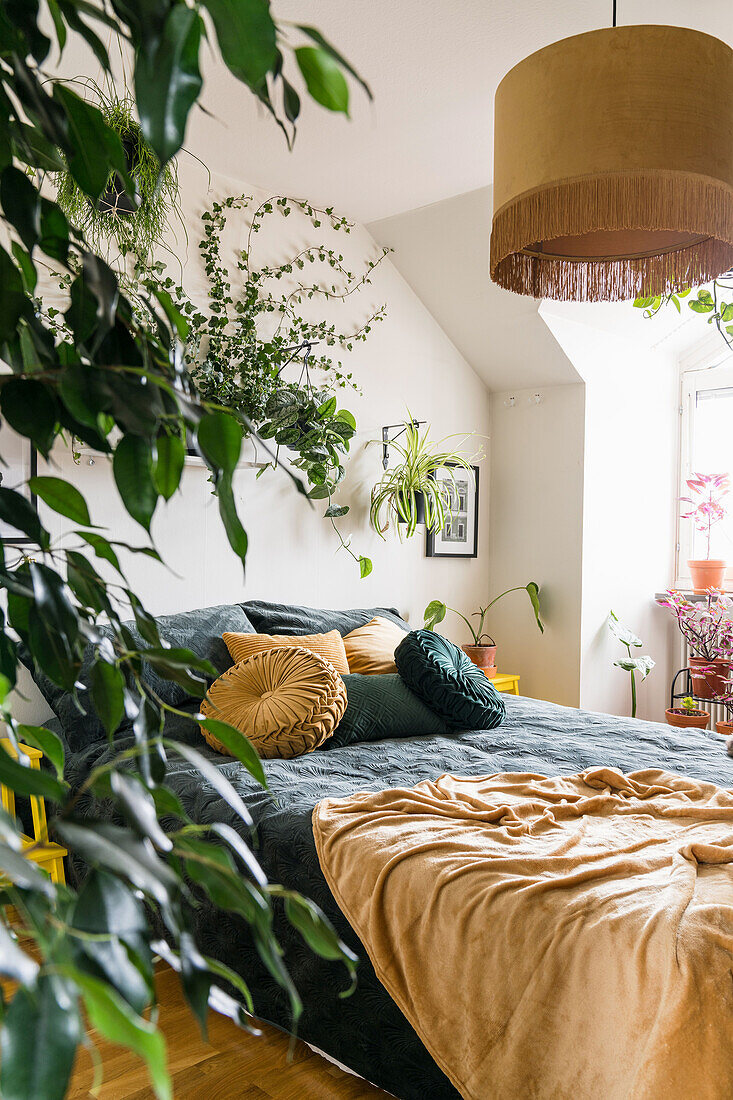 Zimmerpflanzen und Doppelbett im Schlafzimmer in Gelb- und Grüntönen