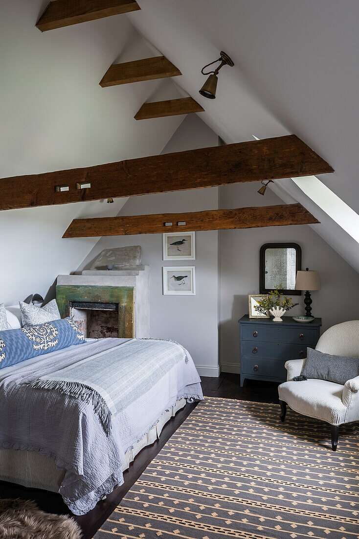 Schlafzimmer im Dachgeschoss mit Holzbalken und blauem Sideboard