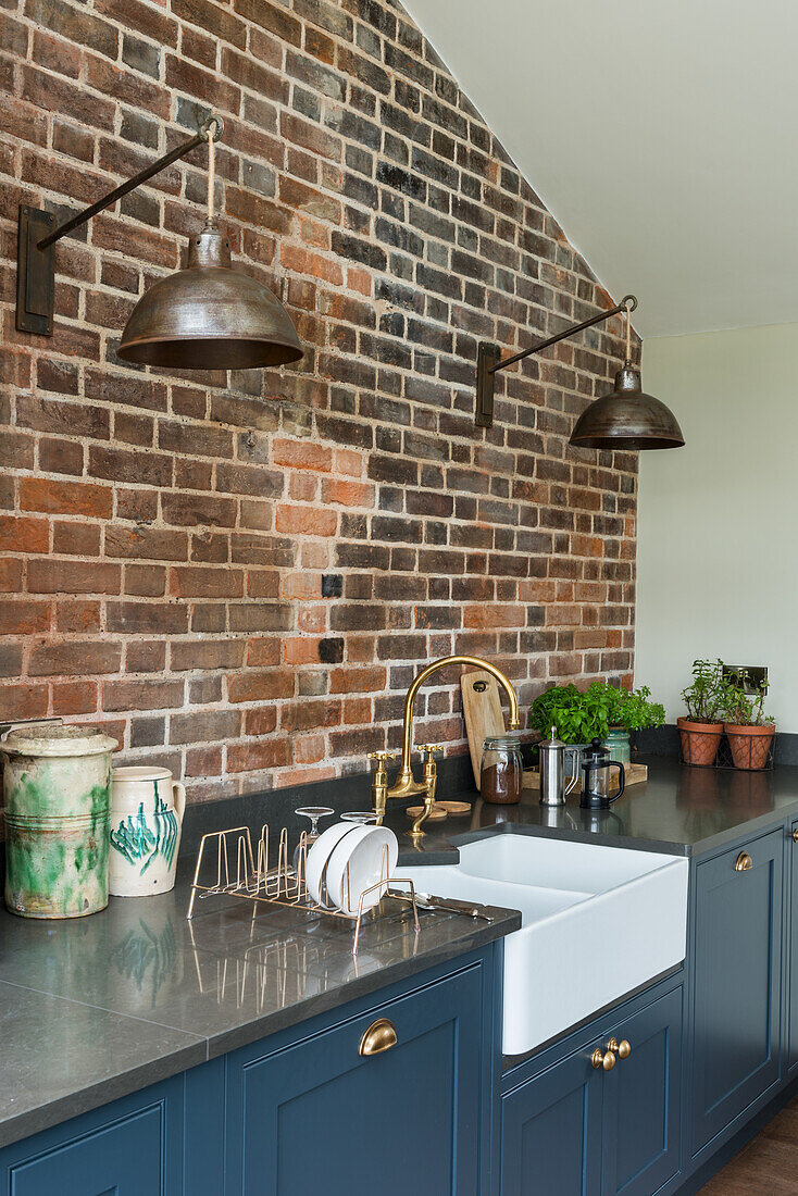 Kitchen with brick wall, blue base units and rustic lamps