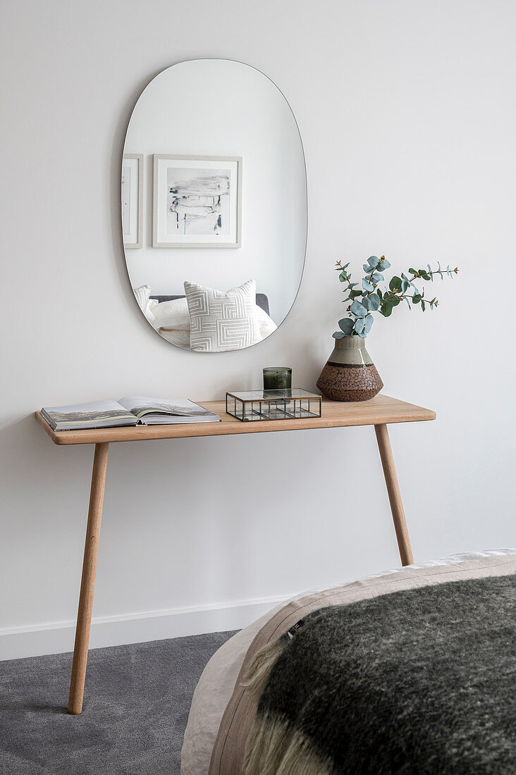 Ovaler Spiegel überm Konsolentisch im minimalistischen Schlafzimmer