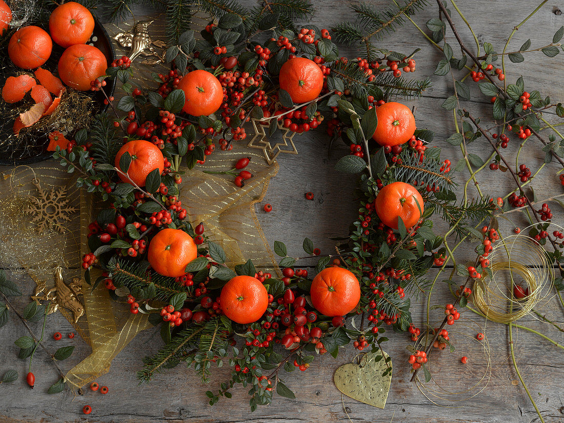 Wreath of cotoneaster berries, rose hips, spruce branches and tangerines