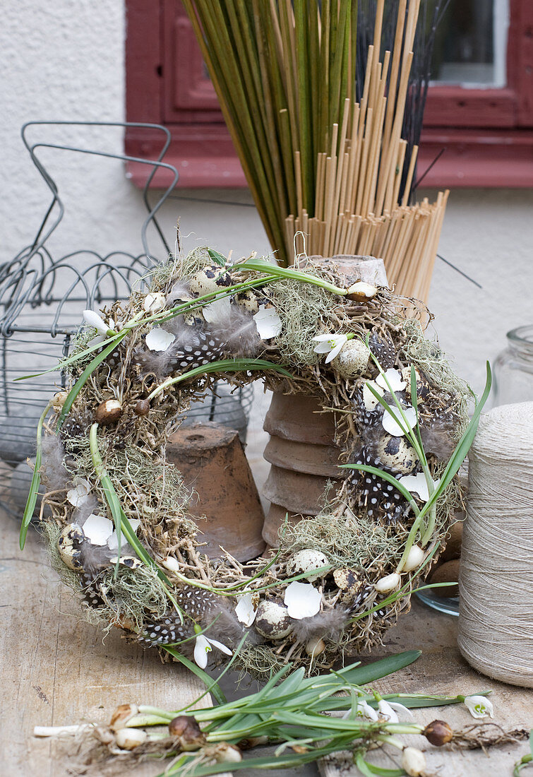 Rustic straw Easter wreath decorated with lichen, feathers and eggshells